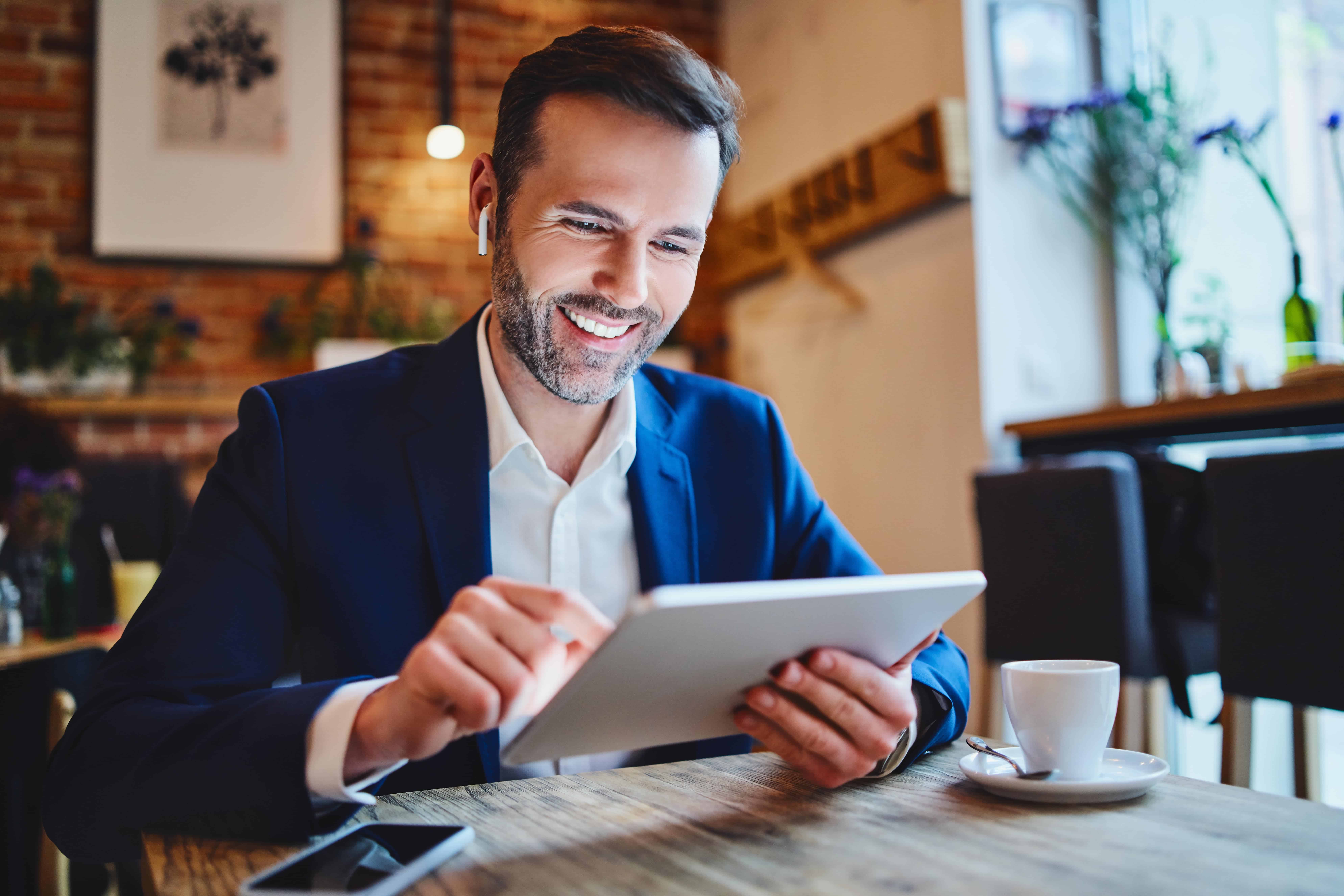 Man smiling while reviewing information on tablet
